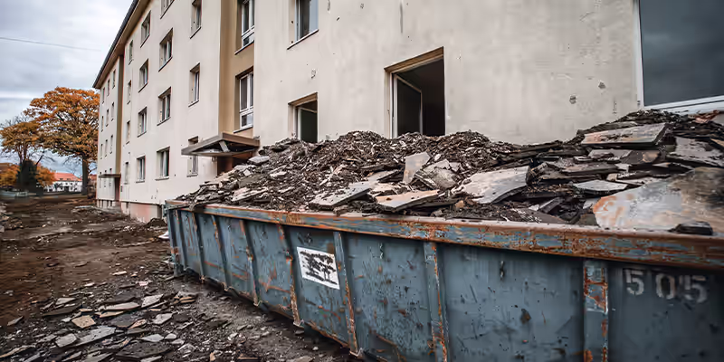 Abbrucharbeiten an einem Mehrfamilienhaus mit Bauschuttcontainer vor der Fassade, durchgeführt von GravisBau in Görlitz
