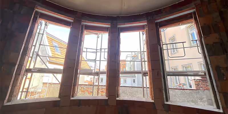 Fenstermontage im Neubau: vorbereitete Fensteröffnungen in einem Rundbogen mit Blick auf die Häuser der Dresdner Innenstadt Parkhotel