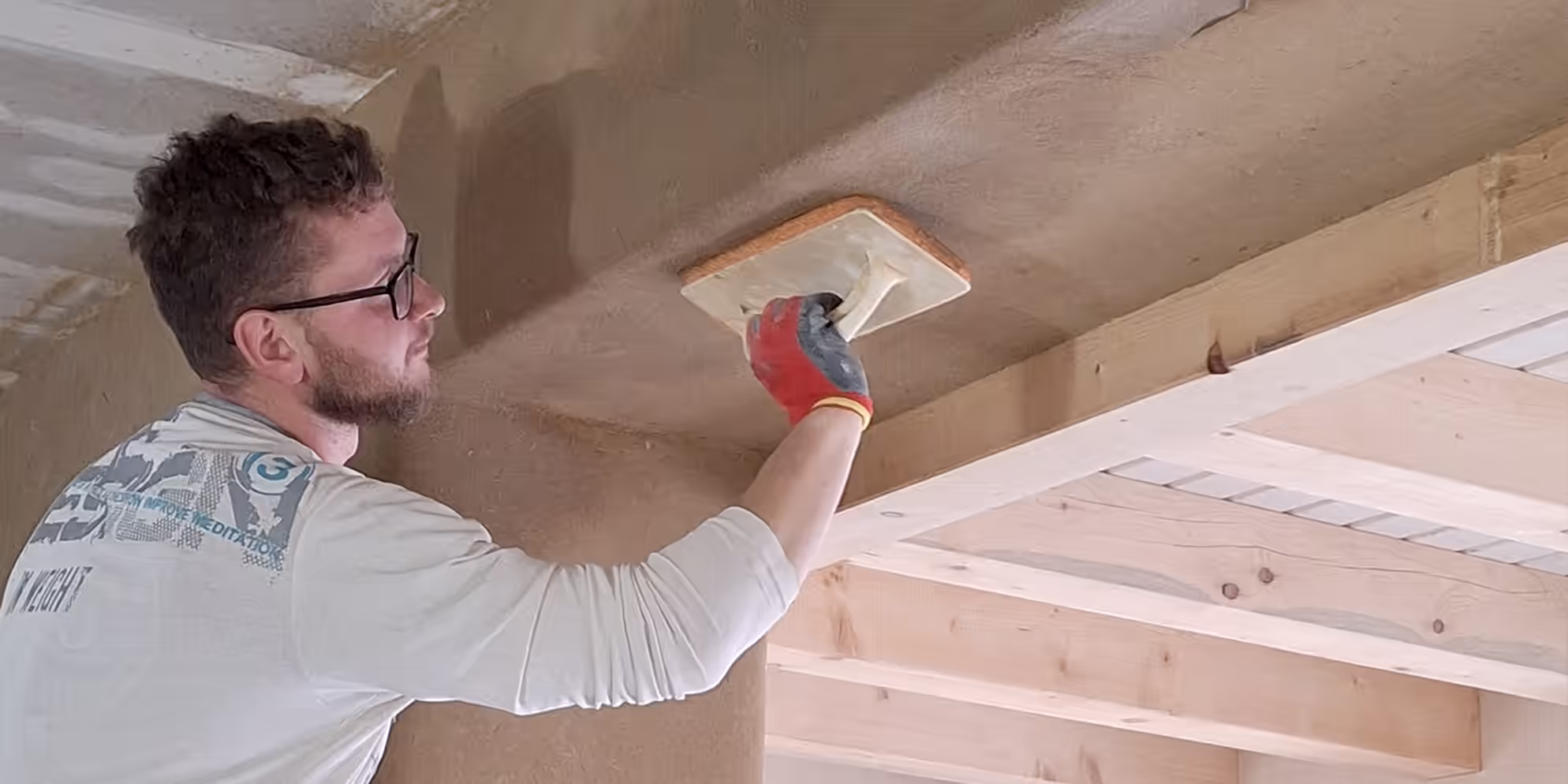 Handwerker trägt Lehmputz als Innenputz an Decke auf
