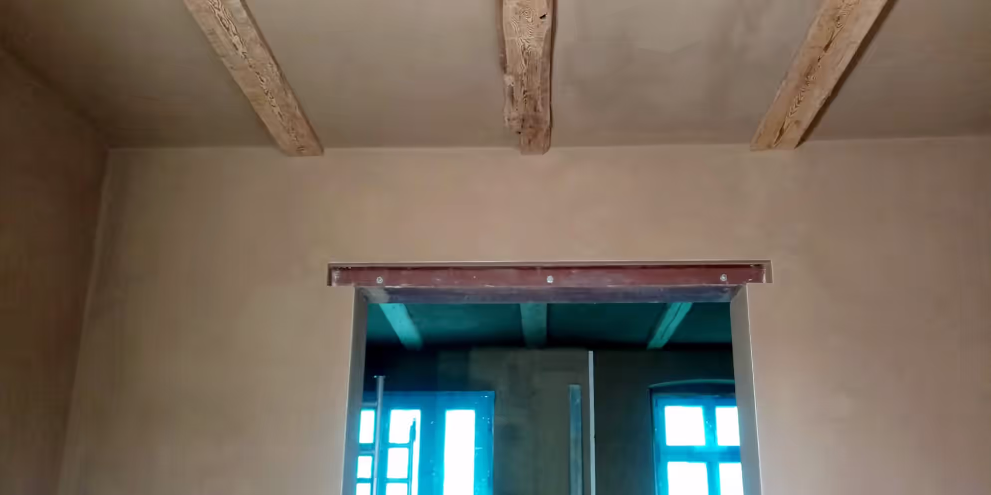 Innenraum mit Lehmputz an Wand und Decke sowie sichtbaren Holzbalken